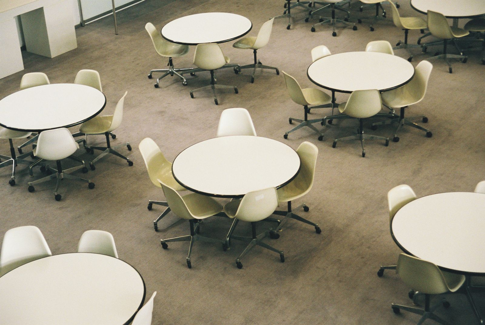 Open commons with round white tables and pale swivel chairs on a light carpet